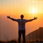 Una persona de edad adulta celebrando un logro personal al levantar los brazos en una cima de montaña, simbolizando superación y transformación personal.